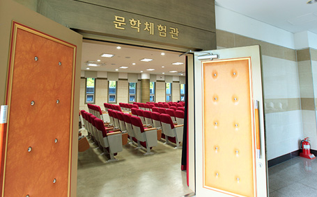 문학체험관 내부모습으로 빨간색 시트로 나열된 의자와 무대앞 단상이 있는 문학체험관