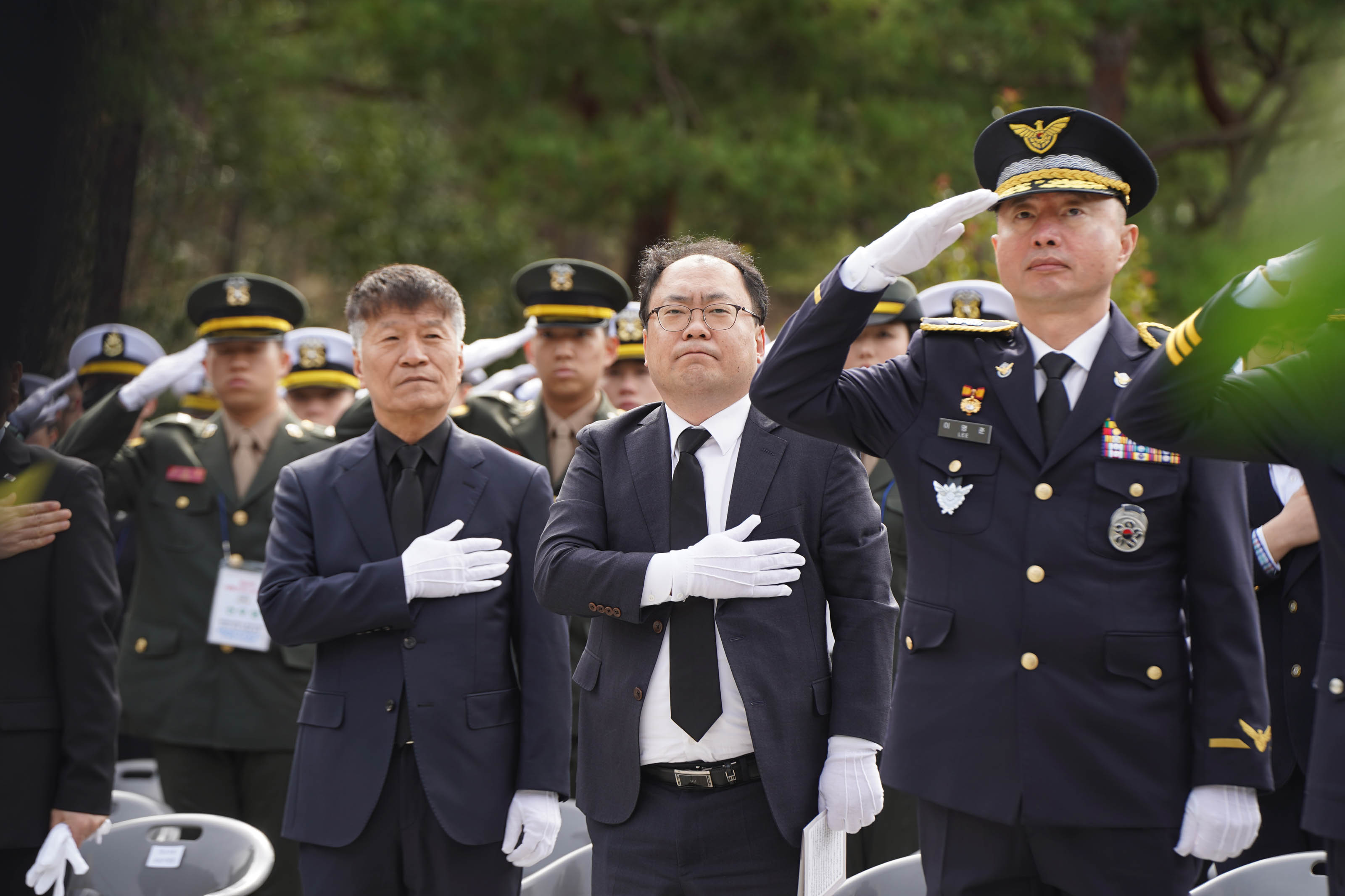 제10회 서해수호의 날 행사에서 참석자들이 경례 또는 묵념을 하고 있는 장면. 중앙에는 검은 정장을 입은 인물들이 흰 장갑을 착용하고 가슴에 손을 얹거나 거수경례를 하고 있다. 군복을 입은 군인들이 뒤편에 일렬로 서서 함께 경례 중이다.