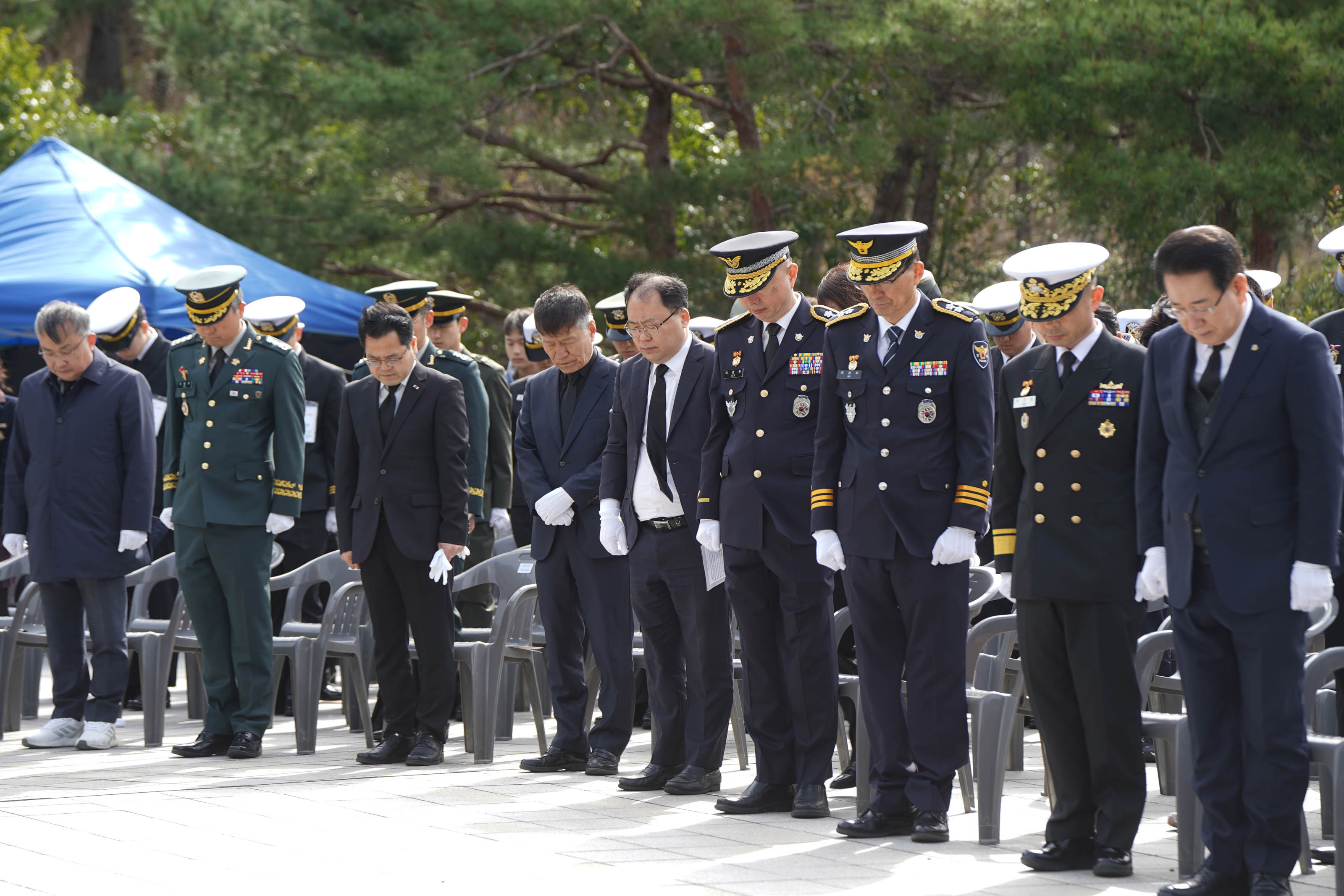 제10회 서해수호의 날 행사 참석자들이 고개를 숙여 묵념하는 장면. 참석자들은 군복과 정장을 착용하고 있으며, 모두 흰 장갑을 착용하고 있다. 배경에는 파란색 천막과 군인들이 보인다.