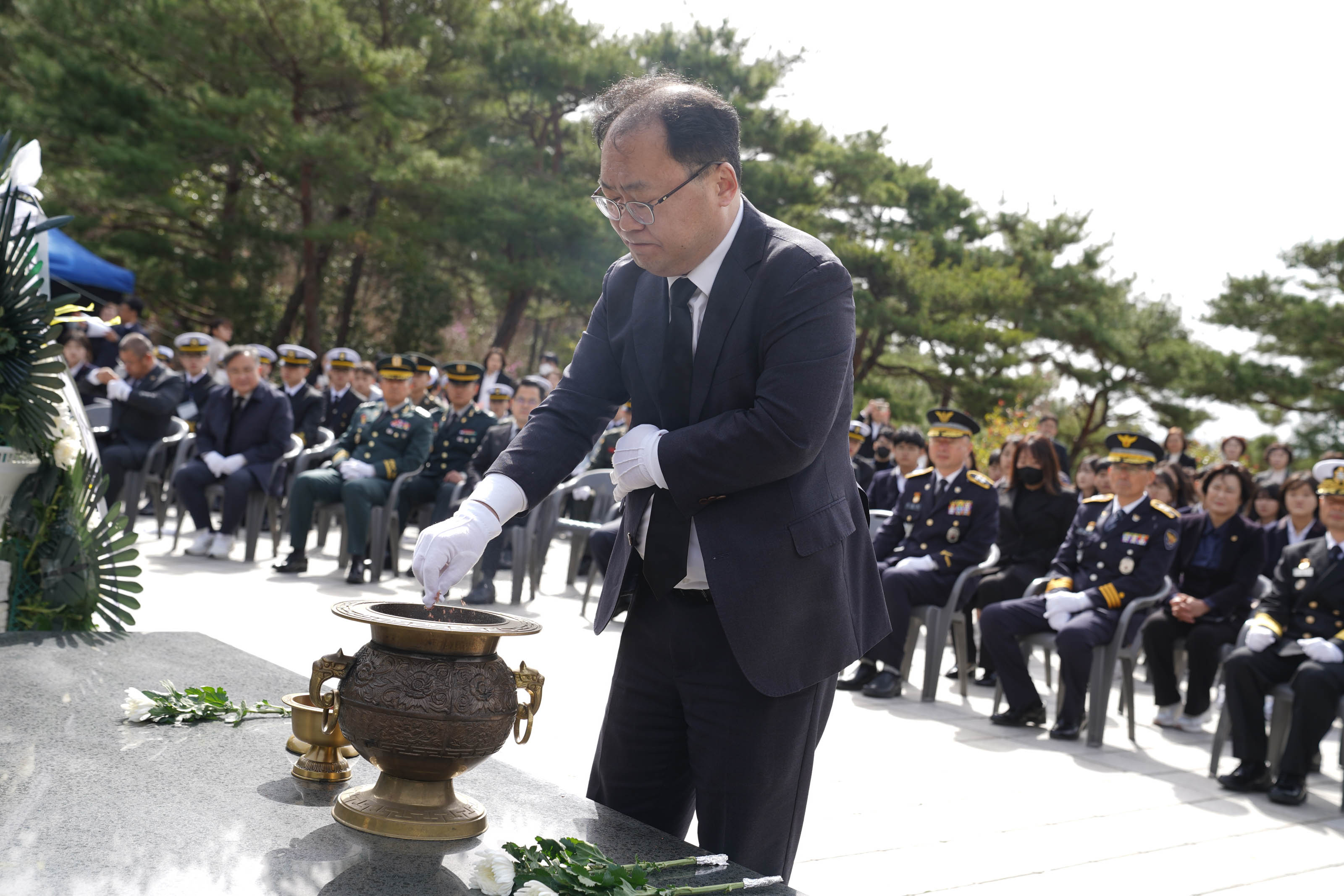 제10회 서해수호의 날 행사에서 목포시장 권한대행 이상진이 검은 정장을 입고 향을 피우며 분향을 하고 있다. 헌화대 앞에는 향로와 국화꽃이 준비되어 있고, 뒷편 좌석에는 군인과 시민들이 경건하게 앉아 있는 모습이 보인다.