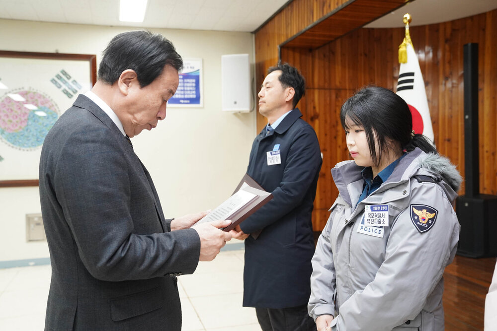 2월 정례조회에서 정장입은 남성이 목포경찰서 역전파출소 직원에게 패를 건내고 있다.