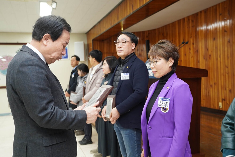 2월 정례조회에서 정장입은 남성이 목포여성 라이온스클럽 직원에게 패를 건내고 있다.