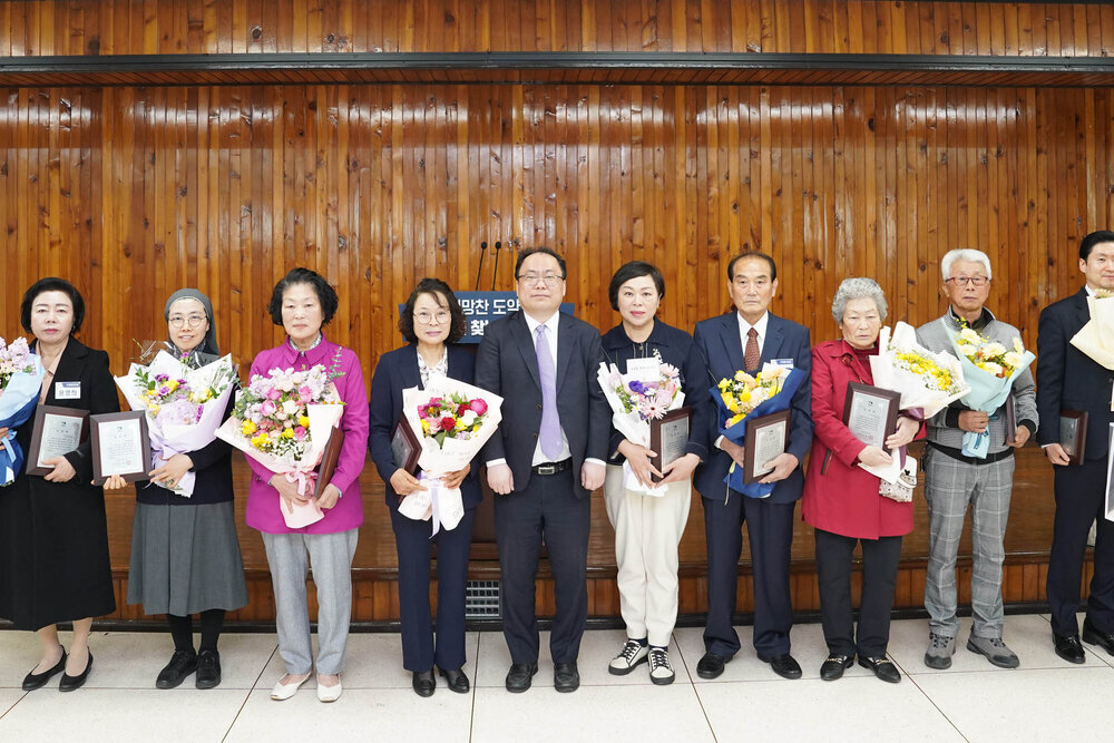 4월 정례조회에서 수상자들이 꽃다발과 표창장을 들고 단체 기념촬영을 하는 모습