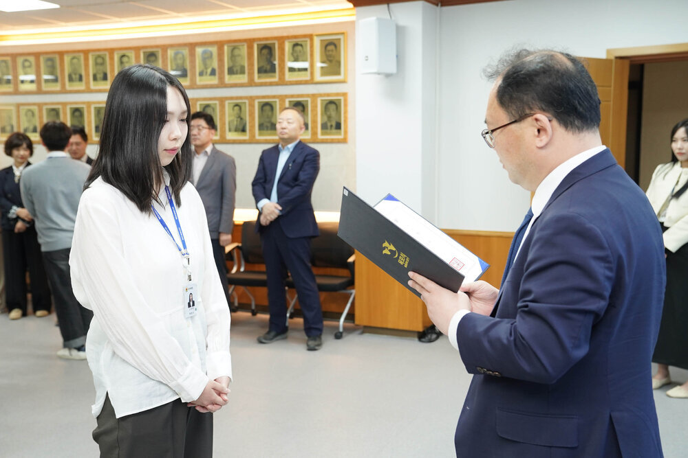수시인사 임용장 수여식에서 정장을 입은 남성이 흰색 블라우스를 입은 여성 직원에게 임용장을 전달하는 모습