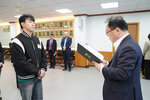 신규자 임용식에서 정장을 입은 남성이 검정 점퍼를 입은 남성 직원에게 임용장을 전달하는 모습