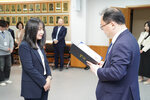 수시인사 임용장 수여식에서 정장을 입은 남성이 네이비 정장을 입은 여성 직원에게 임용장을 전달하는 모습